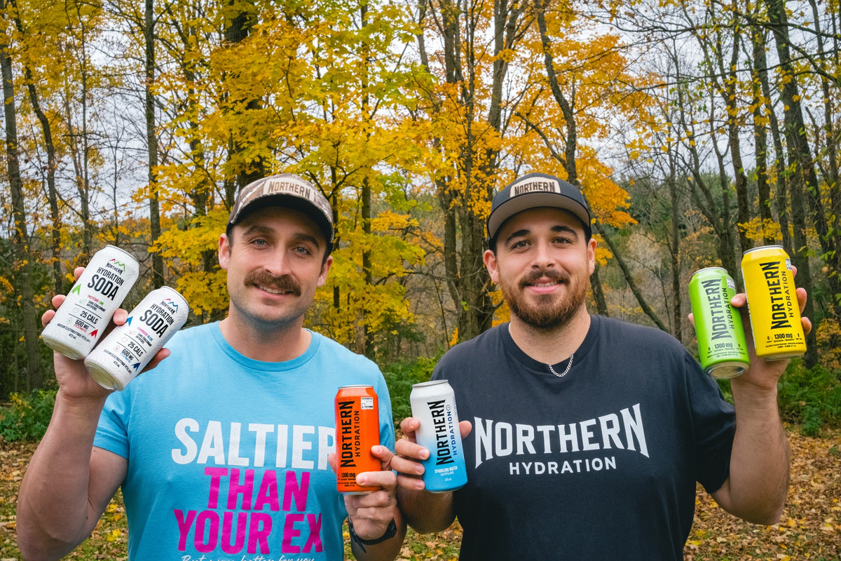 Two Canadian brothers behind Northern Hydration holding Northern Hydration cans outdoors in autumn